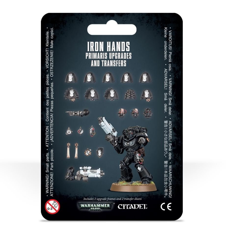 Front of a black-backed Iron Hands Primaris upgrade set, with a black-armored miniature holding a pale blue gun and rows of shoulder pads, heads, weapons and small accessories. The card reads “IRON HANDS” and “PRIMARIS UPGRADES AND TRANSFERS.”
