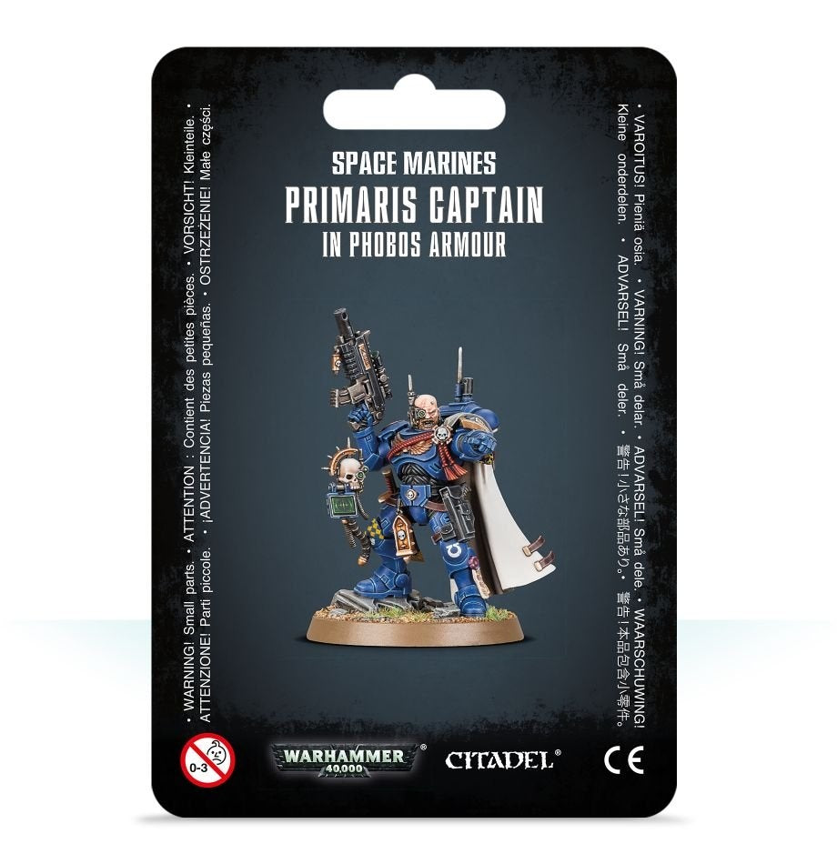 A blue-armored Space Marines captain miniature with a raised rifle, white cape and tan round base is shown on a black backing card. The card reads “SPACE MARINES PRIMARIS CAPTAIN IN PHOBOS ARMOUR” above the figure, with Warhammer 40,000 and Citadel logos below.