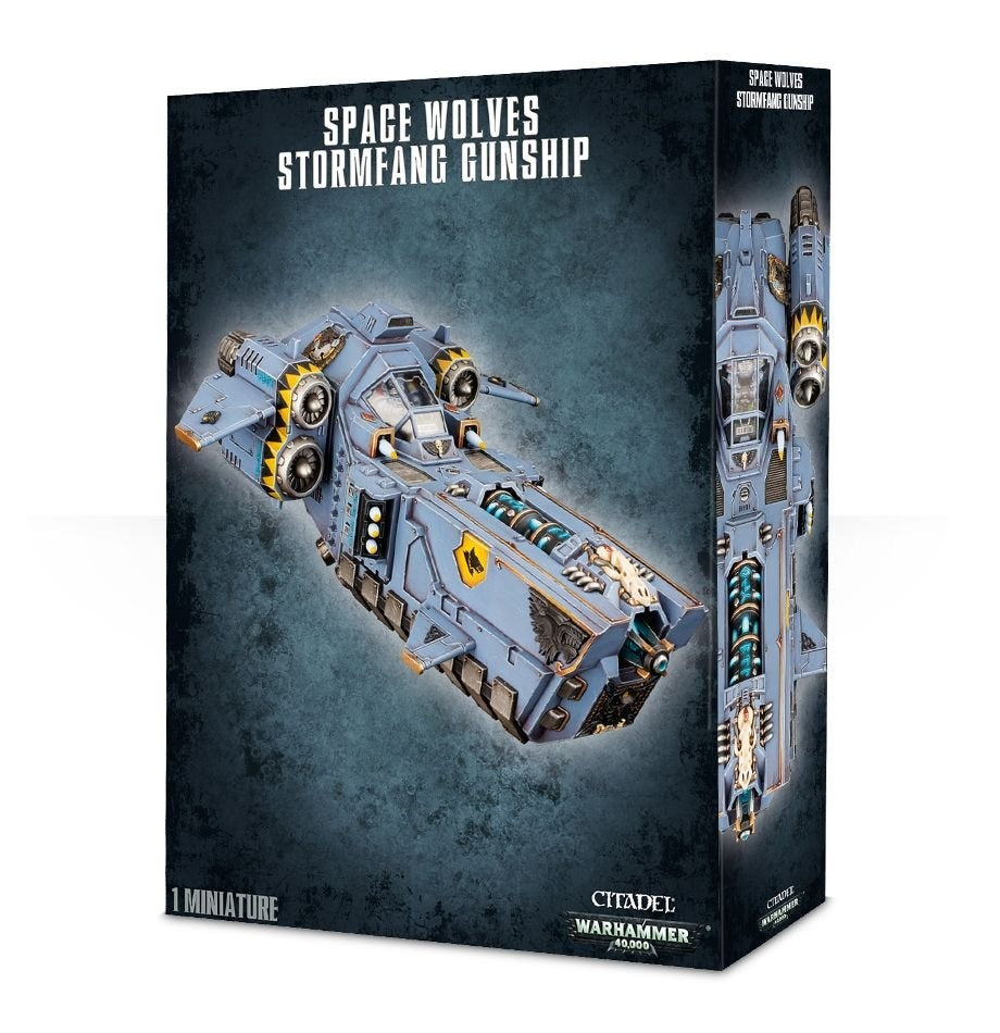 Box for a Stormfang Gunship miniature, showing a blue-gray sci-fi aircraft with yellow accents, twin side engines and forward weapons; a narrow side panel shows a top-down view. The box reads “SPACE WOLVES STORMFANG GUNSHIP” and “1 MINIATURE.”