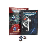 Two overlapping Warhammer 40,000 guide booklets stand behind two painted miniature figures. The front dark blue and black cover shows a close-up armored face and reads “GETTING STARTED WITH” and “WARHAMMER 40,000”; the red cover behind shows battle artwork and the text “YOUR FIRST MODELS.”