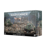 Angled view of a dark gray-green Warhammer miniatures box, showing the front and right side. Artwork depicts green tanks and soldiers on a rocky battlefield; the front reads “WARHAMMER 40,000,” “ASTRA MILITARUM,” “CADIAN DEFENCE FORCE,” and “27 MINIATURES.”