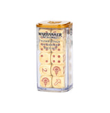 A clear rectangular case with an amber-colored lid holds bone-colored dice marked with dark red pips and symbols, including a skull emblem and directional arrows. The label reads “WARHAMMER THE OLD WORLD TOMB KINGS OF KHEMRI DICE SET.”