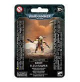 Front of a Warhammer 40,000 miniature package showing a green-skinned warrior with a red feathered crest, layered armor and blades against an orange scene. The packaging reads “WARHAMMER 40,000” and “KROOT FLESH SHAPER.”