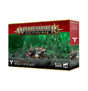 A Warhammer miniature kit box shows Skaven crew operating a large, copper-colored drill machine on rocky ground against a green smoky background. The red-and-black packaging reads “WARHAMMER AGE OF SIGMAR” and “SKAVEN WARP-GRINDER.”