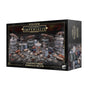 Box for a Warhammer Legions Imperialis terrain set, shown from the front and right side. The dark box depicts gray industrial tanks, pipes, towers and machinery with rust-red details; front text reads “LEGIONS IMPERIALIS” and “MANUFACTORUM IMPERIALIS SECTOR”.