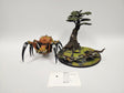 Painted Age of Sigmar Arachnarok spider miniature with an orange-brown body, black-and-white banded legs and large fangs, posed beside a round base featuring a sculpted tree, grassy ground and webbing. A label card reads "HND-31 Age of Sigmar: Skitterstrand Arachnarok".