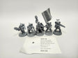 Five unpainted gray Warhammer 40,000 miniature soldiers on round bases, one carrying a large engraved banner and another holding a staff topped with a skull, posed in a row. A white label in front reads "HOT-18" and "Militarum Tempestus: Scions Command Squad".