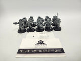 Ten unpainted grey Hearthkyn Warriors miniatures on round black bases, posed with weapons and backpacks, arranged behind two white cards. The top card reads "HQN-24 Warhammer 40,000 Hearthkyn Warriors Leagues of Votann"; the lower card shows a die logo with "FRONTLINE GAMING CHAMPIONS OF TABLETOP".