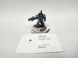 Painted miniature of an Alpha Legion Cataphractii Praetor, a heavily armored warrior in teal and blue-green power armor with a purple cloak, holding a large gun, on a round base with a sculpted white banner and a small blue blade. A white label card in front reads "HOG-28", "Alpha Legion -Legion" and "Cataphractii Praetor".