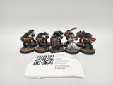 Six painted Warhammer 40,000 Space Marine miniatures in green armor with red weapons on textured round bases, one in white robes holding a chainsword, lined up on a white surface behind a label with a QR code reading "HFA-28" and "Warhammer 40,000 Tactical Squad".