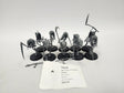 Group of unpainted gray plastic Age of Sigmar Grimghast Reaper miniatures on round black bases, hooded skeletal figures wielding scythes and polearms, with loose weapon parts on the table and a white label in front reading "HJZ-22 Age of Sigmar Grimghast Reapers" and "Nighthaunt".
