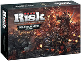 Angled view of the black Risk: Warhammer 40,000 board game box, showing the front and left side. The front features armored sci-fi warriors battling in a fiery scene, with prominent text “RISK” and “WARHAMMER 40,000.”