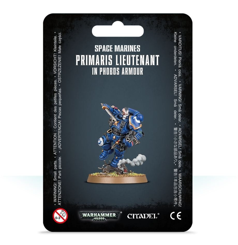 Front of a black blister card package featuring a blue-armored Space Marine miniature with gold trim, a white helmet, and a round scenic base. The card reads “SPACE MARINES” and “PRIMARIS LIEUTENANT IN PHOBOS ARMOUR,” with Warhammer 40,000 and Citadel logos along the bottom.