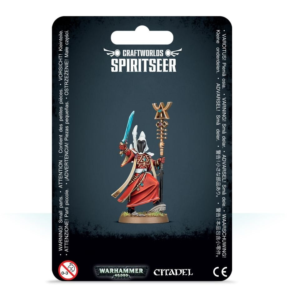 A hooded Aeldari Spiritseer miniature in a flowing red robe, holding a turquoise sword and ornate gold staff, is displayed on a round base against dark packaging. The card reads “CRAFTWORLDS SPIRITSEER,” with “WARHAMMER 40,000” and “CITADEL” logos below.