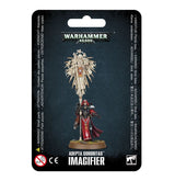 Packaged Adepta Sororitas miniature in black and red armor, standing beneath a tall ivory-colored effigy of a saint on a stanchion. The dark backing reads “WARHAMMER 40,000” and “ADEPTA SORORITAS IMAGIFIER.”
