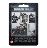 Front of a black, mottled backing card for a Deathwatch upgrade frame, with a collage of black-armored Space Marines, shoulder details, a vehicle and a raised blue sword. The card reads “WARHAMMER 40,000” and “DEATHWATCH UPGRADES.”