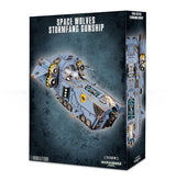 Box for a Stormfang Gunship miniature, showing a blue-gray sci-fi aircraft with yellow accents, twin side engines and forward weapons; a narrow side panel shows a top-down view. The box reads “SPACE WOLVES STORMFANG GUNSHIP” and “1 MINIATURE.”