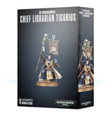 Dark gray box showing front and side panels, with artwork of a blue-armored, cream-robed miniature holding a staff beneath a banner. The front reads “ULTRAMARINES CHIEF LIBRARIAN TIGURIUS” and “1 CITADEL MINIATURE.”