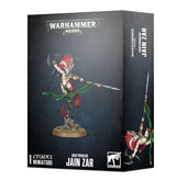 Black Warhammer 40,000 box shown from the front and right side, illustrated with Jain Zar in white armor and a red crest, leaping with a long spear and curved blade as green ribbons trail around her. The box reads “WARHAMMER 40,000,” “CRAFTWORLDS JAIN ZAR” and “1 CITADEL MINIATURE.”