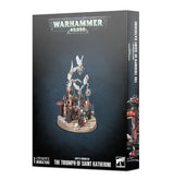 Dark gray Warhammer 40,000 box shown from the front and right side, with artwork of an ornate red, black and gold procession of figures and white-winged cherubs. The front reads “WARHAMMER 40,000” and “THE TRIUMPH OF SAINT KATHERINE.”