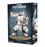 Box for a Tau Empire KV128 Stormsurge miniature, showing a white armored mech with dark joints, teal and orange accents, and heavy weapons standing on an oval base. The side panel shows a second view with a raised weapon; the box reads “TAU EMPIRE,” “KV128 STORMSURGE,” and “1 MINIATURE.”