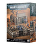 Box for a Warhammer 40,000 terrain set, showing a gray sci-fi bunker and spiked stockade walls with blue and dark-armored miniatures on dusty orange ground; the right side panel shows another scene. The box reads “WARHAMMER 40,000” and “BATTLEZONE: FRONTERIS STC HAB-BUNKER AND STOCKADES.”