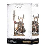 Box front and right side for an Ogor Mawtribes Tyrant miniature, showing a heavily armored ogre holding a long spear and round shield, with skulls hanging overhead. The box reads “OGOR MAWTRIBES TYRANT” and “1 CITADEL MINIATURE,” with Warhammer Age of Sigmar logos.