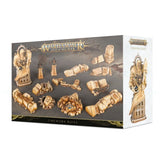 A Games Workshop “Warhammer Age of Sigmar” “Timeworn Ruins” box on a white background. The dark front panel displays tan, weathered-looking ruin terrain pieces, while the pale side panel shows a tall carved statue and the product title.