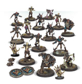 A group of painted Shambling Dead Blood Bowl miniatures on round textured bases, including skeletal and armored players in dark brown, teal and purple gear. Two blue circular markers, small footballs and skeletal-hand accessories are arranged alongside them.