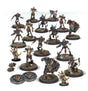 A group of painted Shambling Dead Blood Bowl miniatures on round textured bases, including skeletal and armored players in dark brown, teal and purple gear. Two blue circular markers, small footballs and skeletal-hand accessories are arranged alongside them.