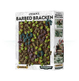 Box of Citadel Barbed Bracken scenery, with a large panel of dense miniature foliage in bright green, teal, purple, and brown on the front. The white patterned packaging reads “CITADEL” and “BARBED BRACKEN”; the side shows small examples in miniature scenes.