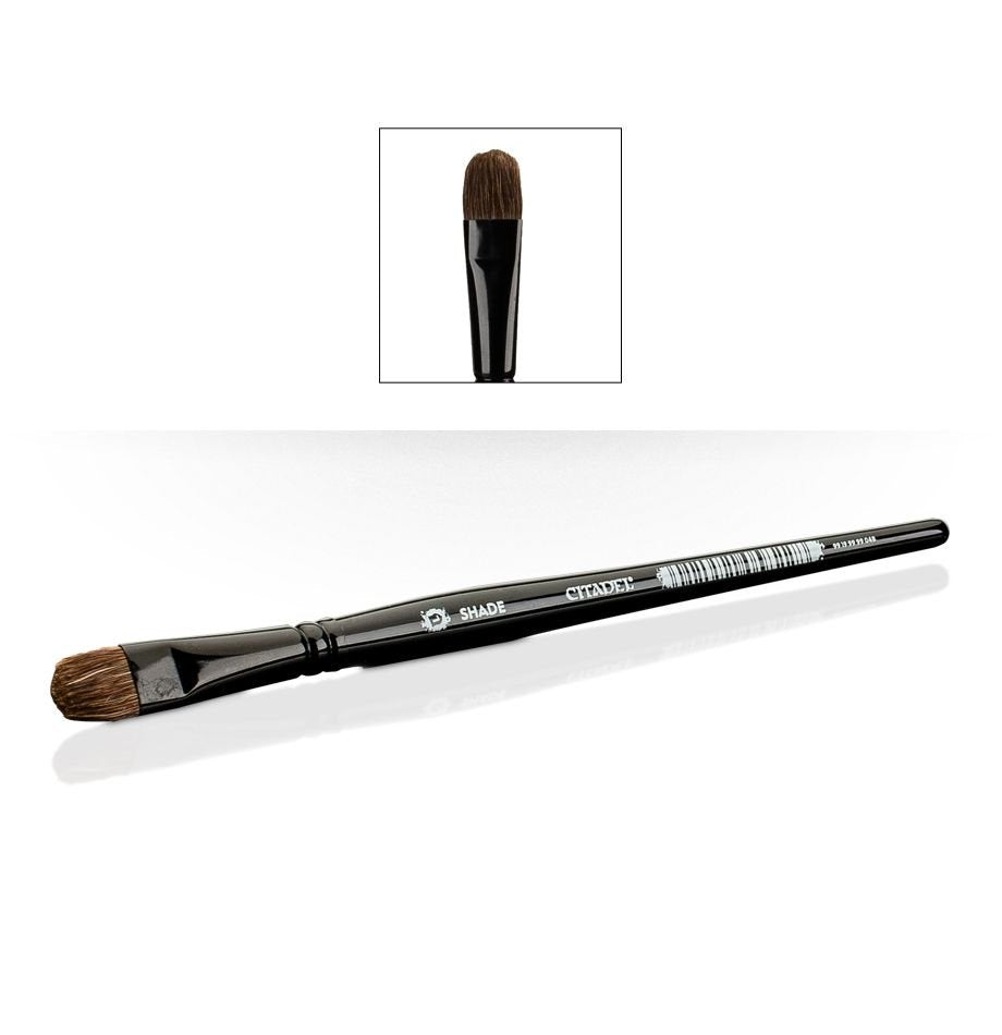 A black shade brush lies diagonally on a white background, with broad rounded brown bristles at one end and white “SHADE” and “CITADEL” lettering on the handle. An inset above shows a close-up of the bristle head.