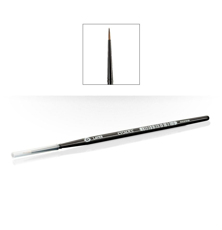 A slim black Citadel layer brush lies diagonally on a white background, with a clear cap over the handle end and a fine pointed brown bristle tip. A small inset shows the tip close up; “CITADEL” and “LAYER” are printed on the handle.