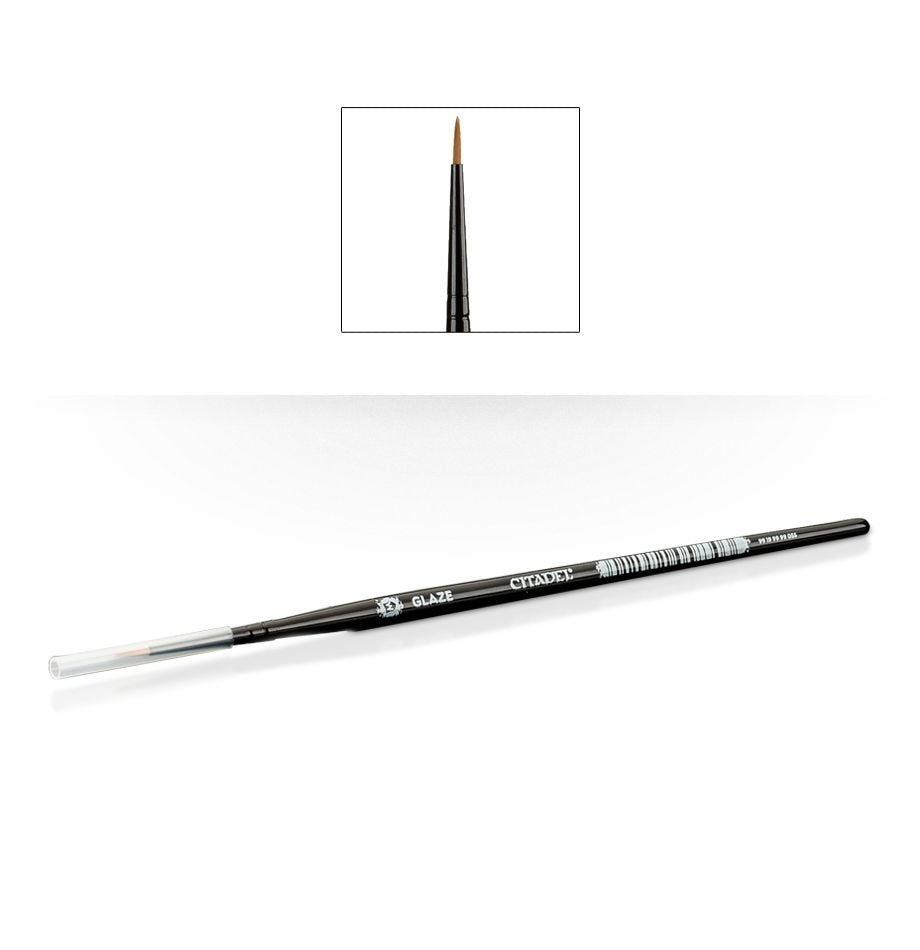 A slim black Citadel glaze brush lies diagonally with a clear protective cap over its pointed brown bristles. White handle lettering reads “GLAZE” and “CITADEL”; an inset above shows a close-up of the tapered brush tip.