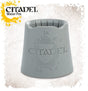 Gray, tapered Citadel water pot shown upright, with a wide base, open top and several grooves around the inner rim. The front has a raised Citadel crest and lettering; the graphic also reads “CITADEL” and “Water Pot.”