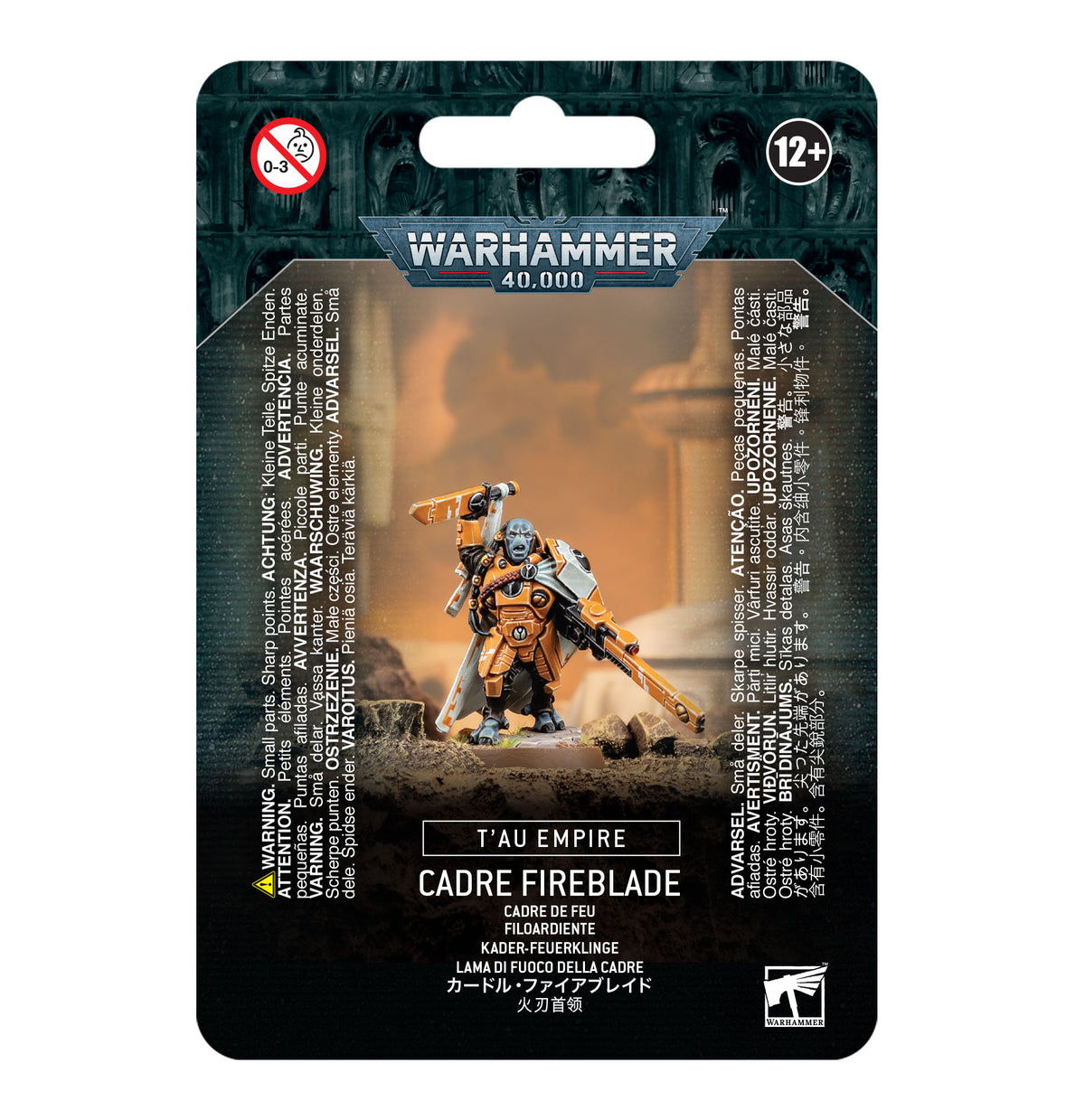 Front of a black and teal Warhammer miniature package showing an orange-armored sci-fi figure holding a long weapon and raising another. The package reads “WARHAMMER 40,000,” “T’AU EMPIRE” and “CADRE FIREBLADE,” with a 12+ age mark.