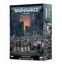 Boxed Warhammer 40,000 miniature terrain set, with artwork of dark, riveted defensive barricades, soldiers and white armored figures before ruined city buildings. The front reads “WARHAMMER 40,000” and “ASTRA MILITARUM AEGIS DEFENCE LINE”; a narrow side panel shows more battlefield artwork.