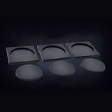 Three dark gray rectangular cavalry base carriers with curved semicircular recesses are arranged above three separate oval miniature bases, all displayed on a dark background.