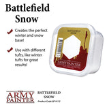 A clear, square plastic tub of white basing material is shown at an angle, with a red, gold and white label reading “Battlefield Snow” and “The Army Painter.” A promotional panel beside it has two checkmarks and text about winter bases and tufts.