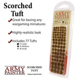 Clear hanging blister pack filled with rows of small brown, scorched-looking tufts in three sizes. The label reads “THE ARMY PAINTER” and “SCORCHED TUFT”; promotional text says it includes 77 tufts.