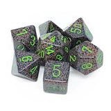 Seven speckled earth polyhedral dice are arranged in a cluster on a white background. Their gray faces are mottled with black and muted pink flecks, with bright green numerals and thin white divider lines.