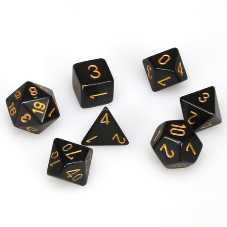 Seven glossy black polyhedral gaming dice are arranged separately on a white background, each marked with raised-looking gold numerals. The set includes dice with triangular, square and many-sided faces.