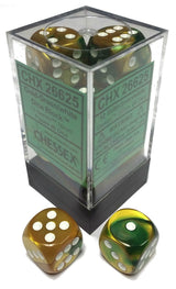 Gold and green marbled D6 dice with white pips sit inside a clear display case, with two loose dice in front showing different faces. The green label reads “CHESSEX” and “CHX 26625.”