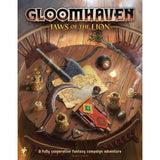 Gloomhaven: Jaws of the Lion board game box cover shows a parchment map, axe, red-and-gold weapon, coins, and fantasy creatures scattered across a wooden table. The title reads “GLOOMHAVEN” and “JAWS OF THE LION”; smaller text says “A fully cooperative fantasy campaign adventure.”