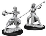 Two monochrome gray female half-elf monk miniatures stand on rocky sculpted bases with black rims. The left figure reaches forward with one hand and wears layered robes; the right holds a long staff diagonally while posed in a wide stance.