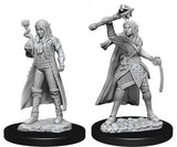 Two unpainted gray female elf cleric miniatures on black round bases, shown side by side: one holds a small orb, while the other raises a large axe and holds a curved blade, both wearing layered armor and capes.