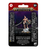 Front of a red, purple and black Warhammer Age of Sigmar package showing a bronze-armored duelist with a curved sword and ornate shield standing on skulls. The card reads “WARHAMMER AGE OF SIGMAR” and “HEDONITES OF SLAANESH LORD OF HUBRIS.”