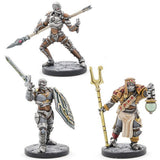 Three painted Warforged tabletop miniatures stand on round bases against a white background: a gray armored figure with a spear at the top, a silver-gray sword-and-shield fighter at lower left, and a robed figure holding a gold staff and cup at lower right.