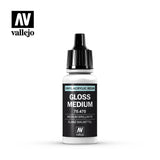 A small white dropper bottle with a tall black ribbed cap and black label reading “GLOSS MEDIUM” and “70.470,” topped by a cyan strip marked “VINYL-ACRYLIC RESIN.” A Vallejo logo appears at the upper left on a white background.