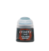 A small, squat Citadel paint pot stands upright with a dark body, red-and-black label, and pale translucent domed cap. The label reads “CITADEL,” “BASE,” and “CALIBAN GREEN” in white lettering.